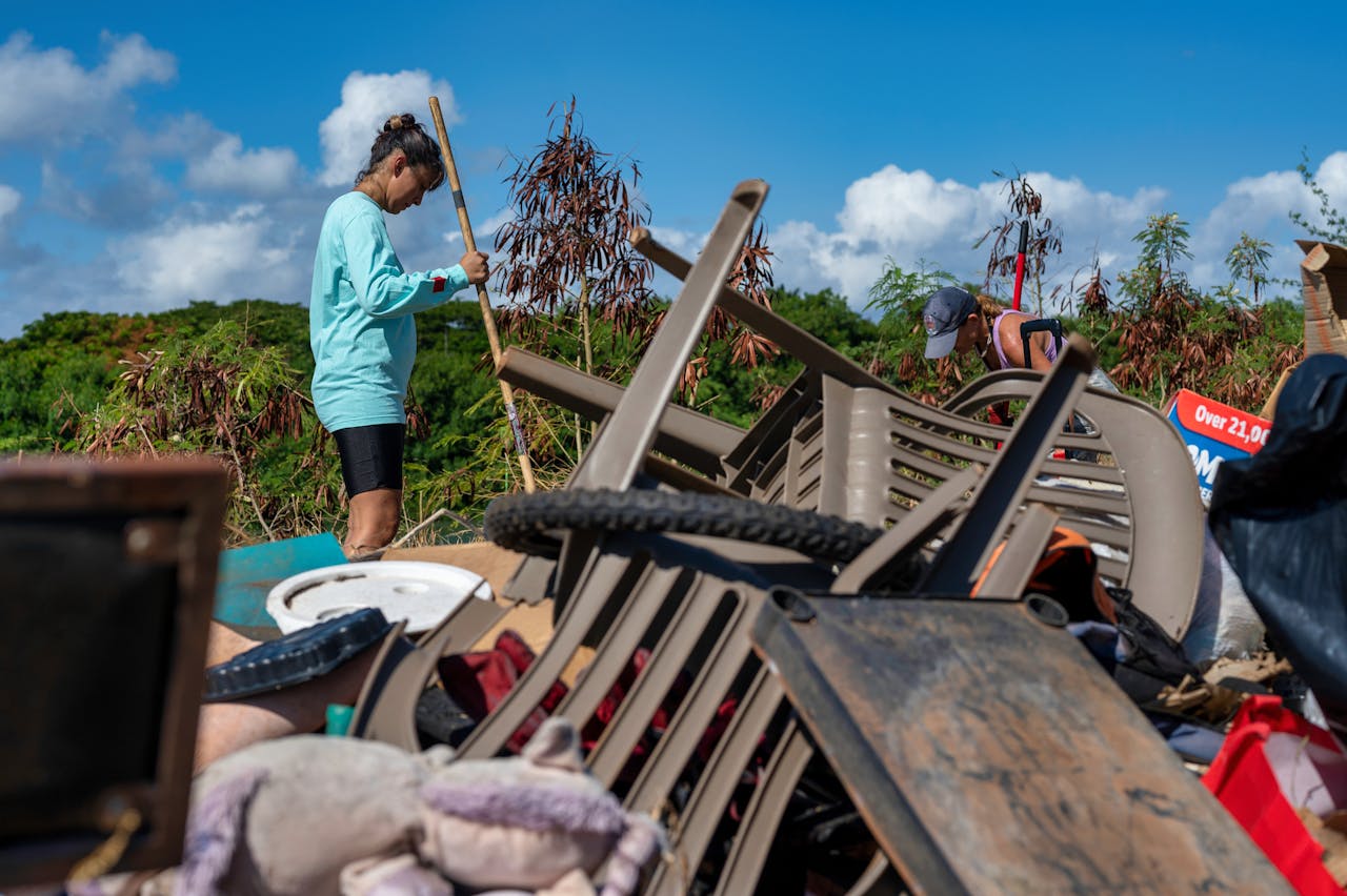 Two women cleaning up a pile of garbage at an outdoor site in Hawaii. Eco-friendly activity.